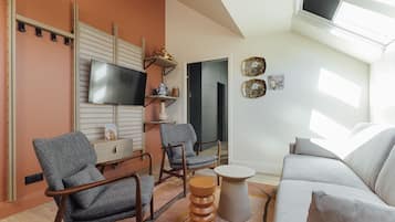 Una sala de estar moderna con un sofá, dos sillones, un televisor y una mesita.