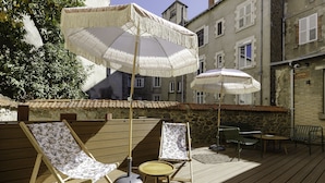 A wooden deck with two lounge chairs, a small table, and two umbrellas. - Hôtel Préfecture - 100m de l'Opéra - Encore Mieux (Limoges)