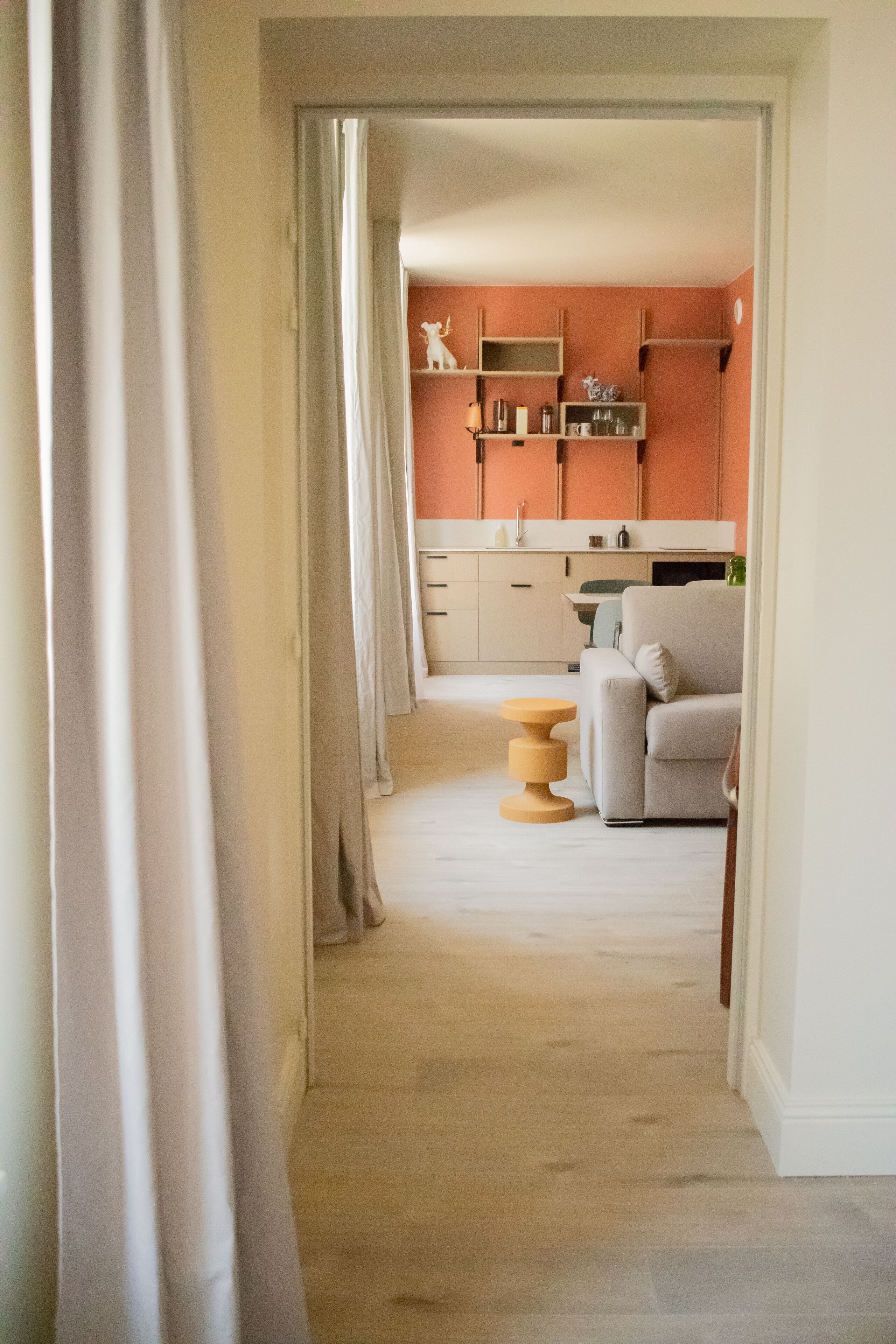 Un pasillo que conduce a una cocina con un sofá y una mesa redonda de madera.