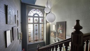 A staircase with a wooden railing, a stained glass window, and wall-mounted art. - Hôtel Préfecture - 100m de l'Opéra - Encore Mieux (Limoges)
