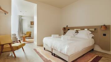 A modern bedroom with a large bed, a wooden headboard, a chair, and a view of the living area.