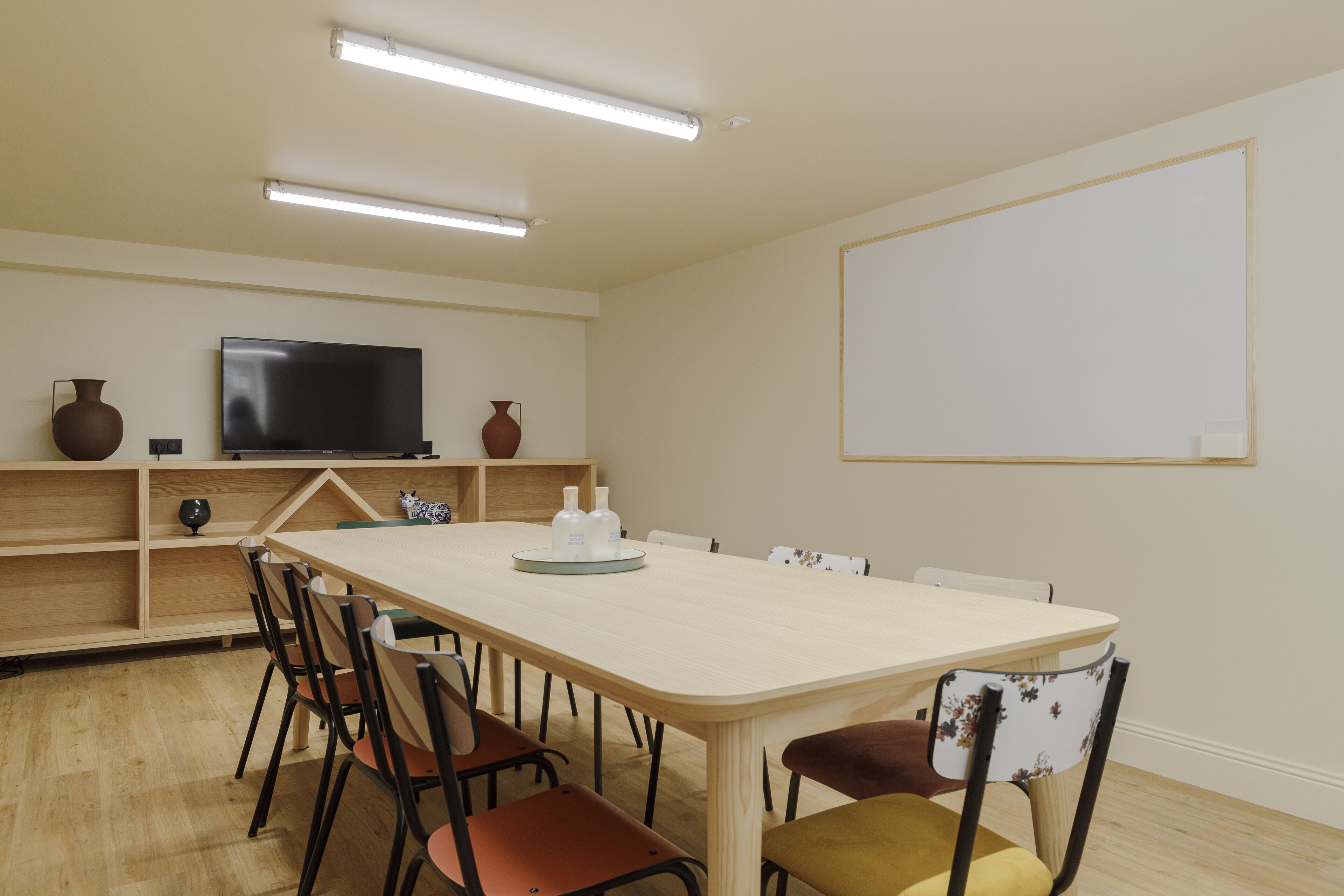 Une salle de conférence équipée d’une longue table, de chaises, d’un téléviseur et d’un tableau blanc.
