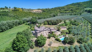 A stone building with multiple rooms, surrounded by lush greenery and a swimming pool. - Podere Le Corone 14, Emma Villas (Perugia)