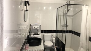 A modern bathroom with a glass shower enclosure, a toilet, a bidet, and a sink with a black basin. - 1 Bedroom Apartment in Tresques (Tresques)