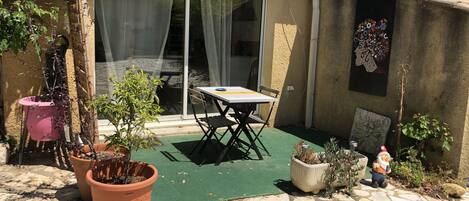 A patio with a table and chairs, potted plants, and a child playing.
