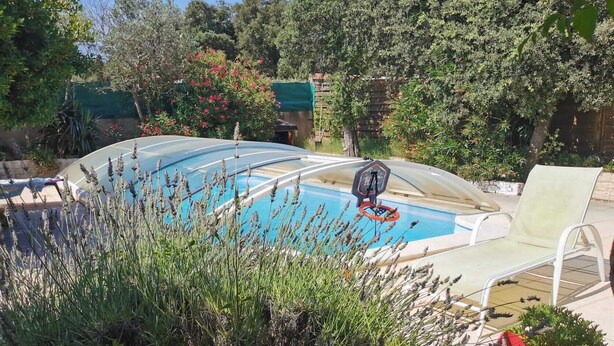 A swimming pool with a basketball hoop, surrounded by lush greenery and a lounge chair. - 1 Bedroom Apartment in Tresques (Tresques)