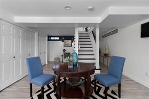 Cozy living area with a round table and two comfortable chairs, a stylish rug, and a staircase leading upstairs.