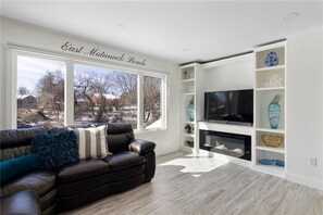 Enjoy a view of East Mainuck Beach from this living room with a sofa, flat-screen TV, and fireplace.