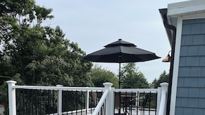 Une terrasse avec une balustrade blanche, des marches grises et un parasol noir.