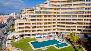 A multi-story hotel with a central courtyard featuring a swimming pool and sun loungers.