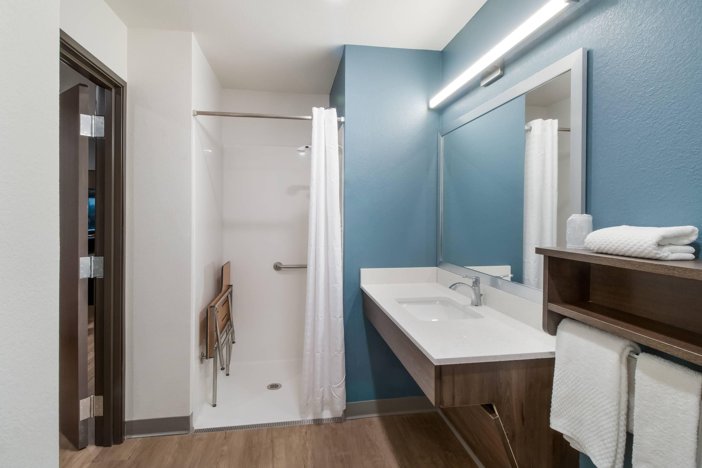 A modern bathroom with a shower, a sink, and a mirror.