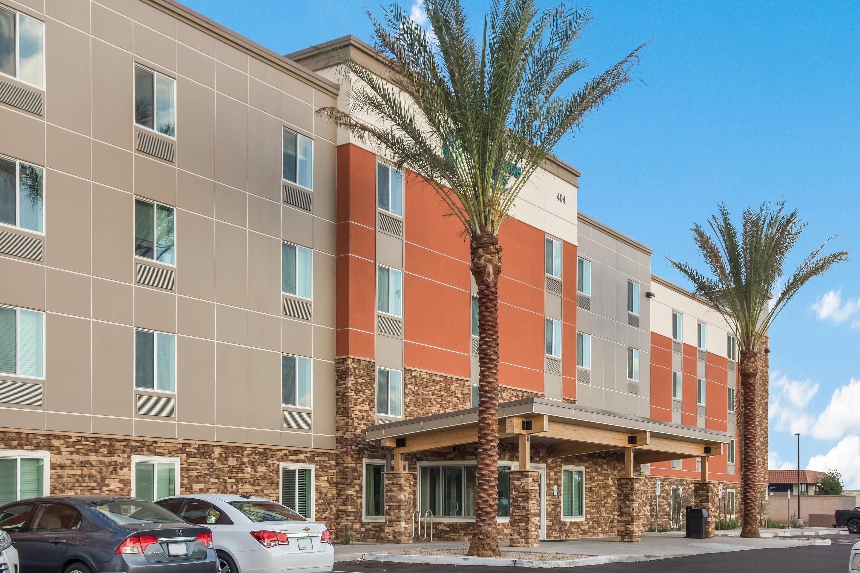 Un hotel de varios pisos con fachada moderna, que combina texturas de piedra y estuco.