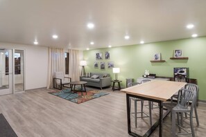 A modern living room with a dining area, a sofa, a coffee machine, and a small table. - Woodspring Suites Mesa Chandler (Mesa)
