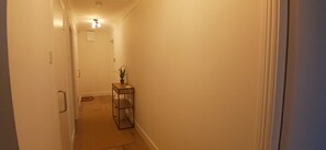 A narrow hallway with a door on the left and a small table with a plant on the right. - Stylish 2 Double Bed apartment in central Dublin (Dublin 1)