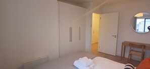 A bedroom with a bed, a wardrobe, a mirror, and a door leading to another room. - Stylish 2 Double Bed apartment in central Dublin (Dublin 1)