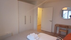 A bedroom with a bed, a wooden chair, a wardrobe, and a mirror on the wall. - Stylish 2 Double Bed apartment in central Dublin (Dublin 1)