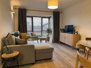 A modern living room with a sofa, armchair, dining table, and TV. - Stylish 2 Double Bed apartment in central Dublin (Dublin 1)