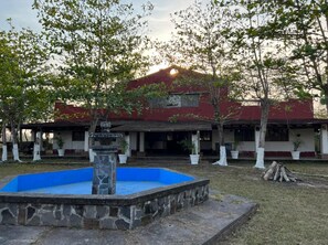 Guests can enjoy a peaceful atmosphere on the covered porch surrounded by lush greenery and a serene stone fountain.