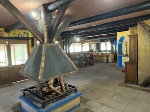 Cozy gathering space with a large metal stove, wooden tables, and comfortable seating.