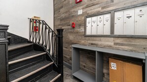 Una escalera con barandillas negras que lleva a un espacio con taquillas y un muro de madera.