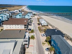 Un quartier résidentiel situé sur la côte, avec des propriétés donnant sur la plage, une route asphaltée et un chemin piétonnier menant à la plage.