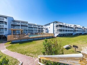 A modern hotel with multiple balconies, a pool area, and a well-maintained lawn.