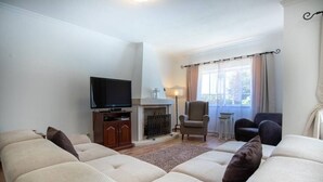 A living room with a fireplace, a television, and a sofa set.