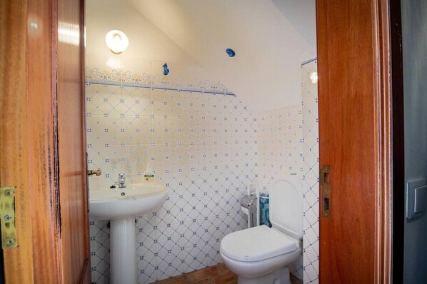Ein Badezimmer mit weißem Waschbecken, WC und Duschbereich.