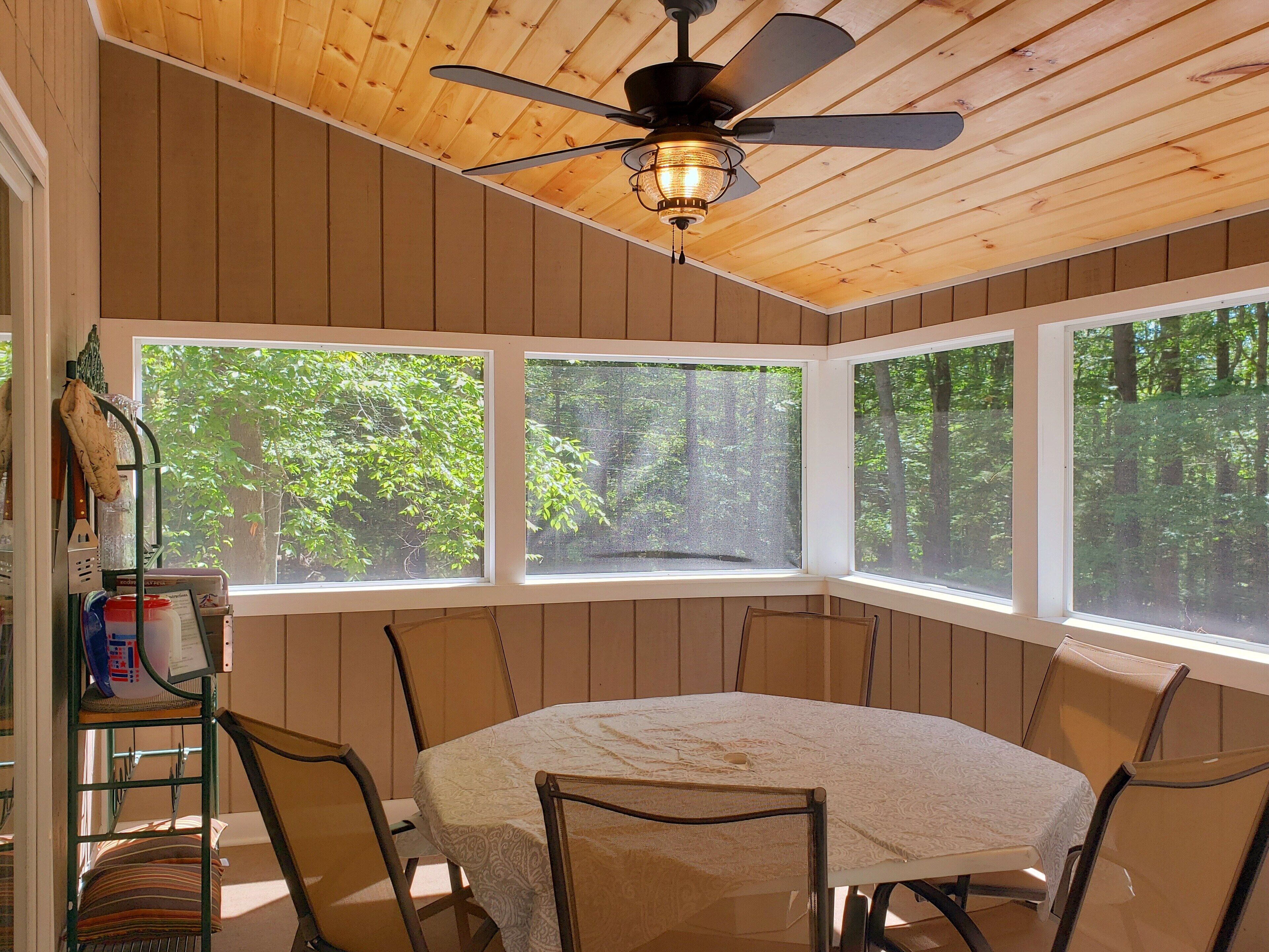 Un coin repas avec une table ronde, des chaises et un ventilateur de plafond.