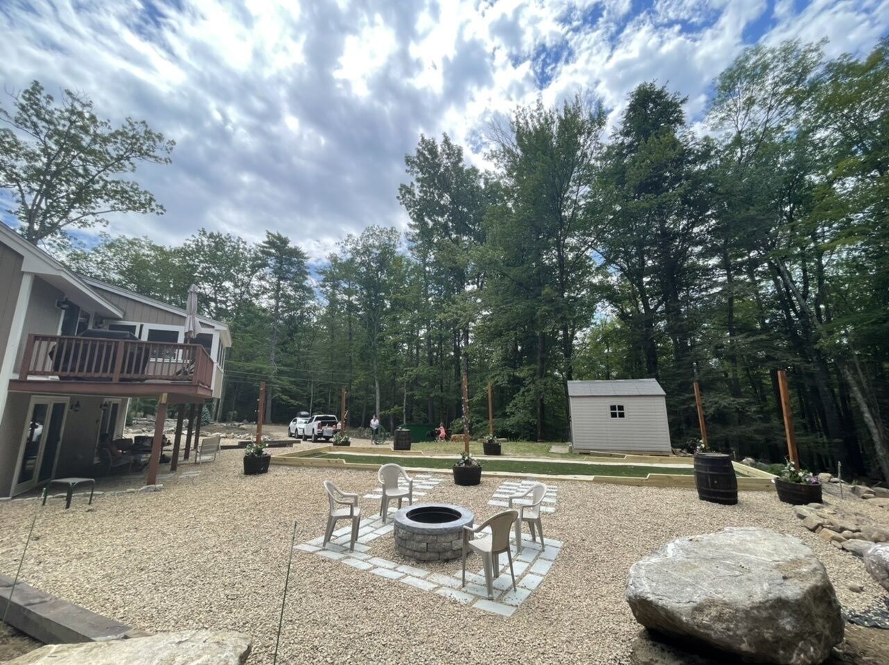 A backyard with a fire pit, outdoor seating, a shed, and a house with a balcony.