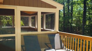 Eine überdachte Terrasse mit zwei Liegestühlen und einem Holzgeländer.