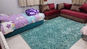 Un dormitorio con cama, sofá y una alfombra estampada.