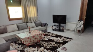 Una sala de estar con un sofá, una mesa de centro, un televisor y un radiador.