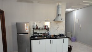 Una cocina con un refrigerador de acero inoxidable, estufa a gas, armarios blancos y una salpicadura de mármol.