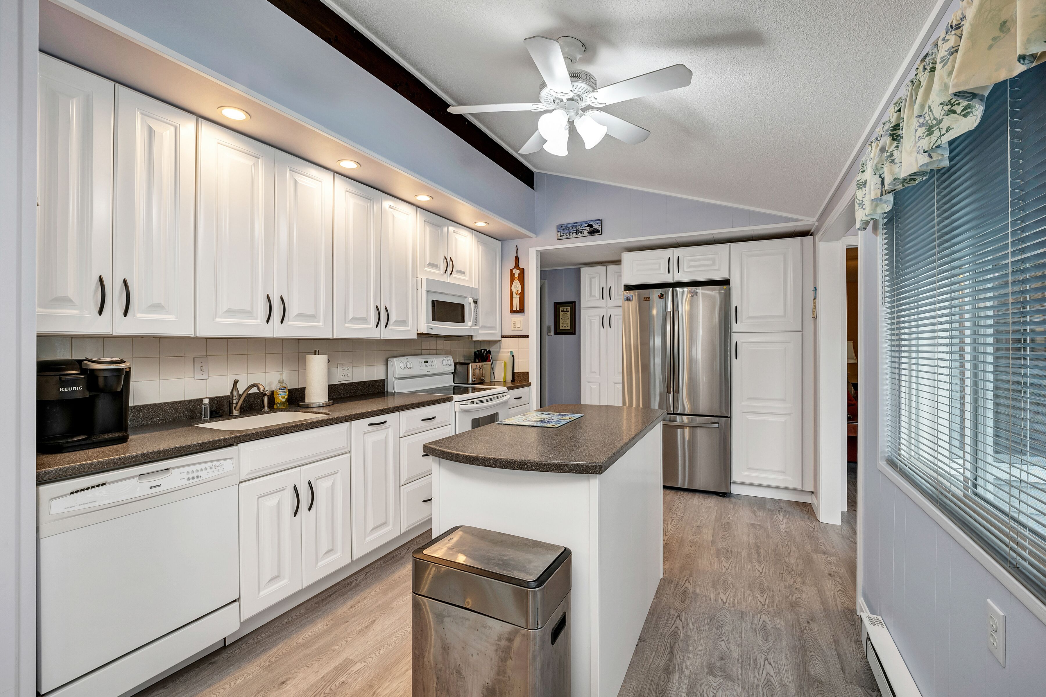 A modern kitchen with white cabinets, stainless steel appliances, and a central island.