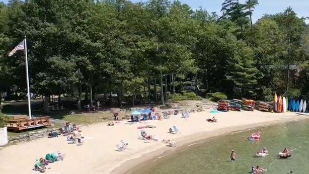 Una spiaggia con acque cristalline, ombrelloni e persone che si rilassano.