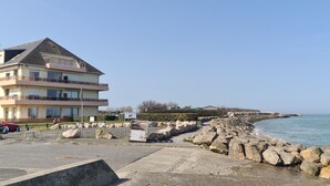 A coastal hotel with a large building, a rocky breakwater, and a clear view of the sea. - Le Panoramic - 180° sea view & port - Balcony - Elevator - Garage - Waterfront (Grandcamp-Maisy)