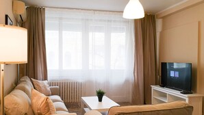 Un salon avec un canapé, une table basse, un téléviseur et une lampe.