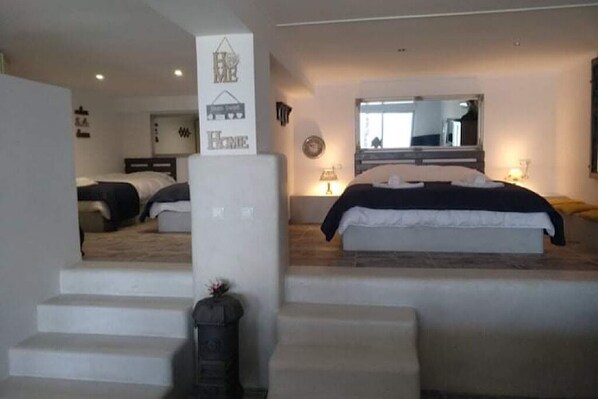 A hotel room with a large bed, a mirror, a staircase, and a sign that says "Home". - Bloomy’s fairytale (Νέα Κορώνη)