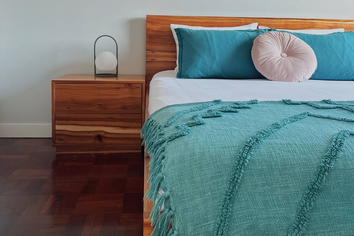 A neatly arranged bedroom with a wooden bed, a bedside table, and a nightstand.