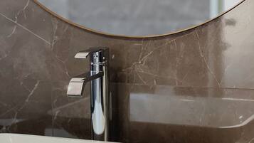 A bathroom sink with a modern faucet and a marble backsplash.