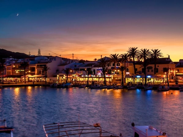 A waterfront area with buildings, palm trees, and boats.