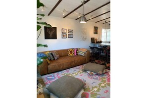A cozy living room with a brown leather sofa, colorful cushions, and a patterned rug.