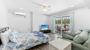 Ein modernes Zimmer mit einem Bett, einem grünen Sofa, einem Fernseher und einem Deckenventilator.