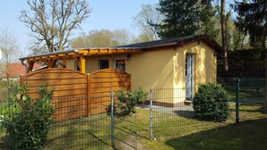Een gelijkvloers huis met een houten poort en een metalen hek.