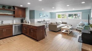 Una cocina amplia con armarios de madera, lavavajillas y un comedor con sofá y mesa de centro.