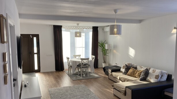 Ein modernes Wohnzimmer mit einer Couch, einem Esstisch und einer kleinen Küche.