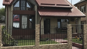 Ein zweistöckiges Haus mit rotem Ziegeldach, einem Balkon und einem umzäunten Garten.