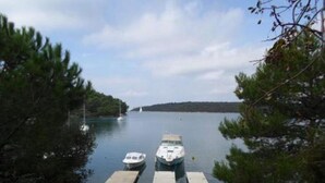 A marina with two boats docked at a concrete pier surrounded by trees.