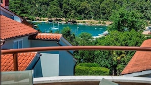 A balcony with a table and chairs, overlooking a marina with boats and a forested area.